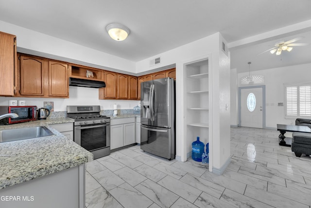 kitchen featuring pendant lighting, sink, light stone counters, ceiling fan, and stainless steel appliances