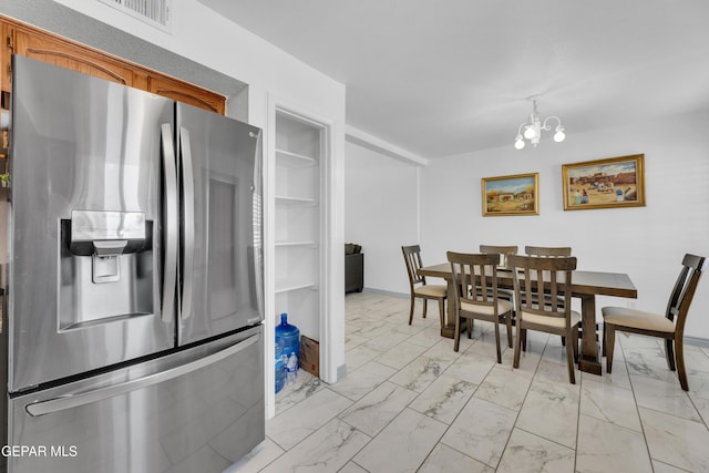 interior space with stainless steel refrigerator with ice dispenser and an inviting chandelier