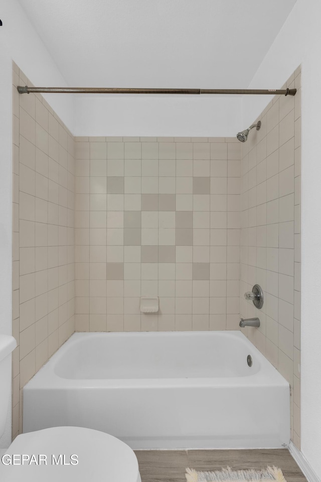 bathroom with tiled shower / bath, hardwood / wood-style floors, and toilet