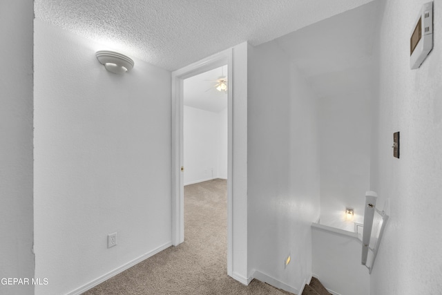 hallway featuring light colored carpet and a textured ceiling