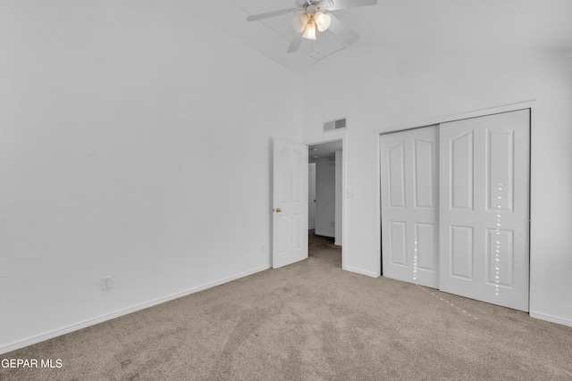 unfurnished bedroom featuring ceiling fan, a closet, high vaulted ceiling, and light carpet