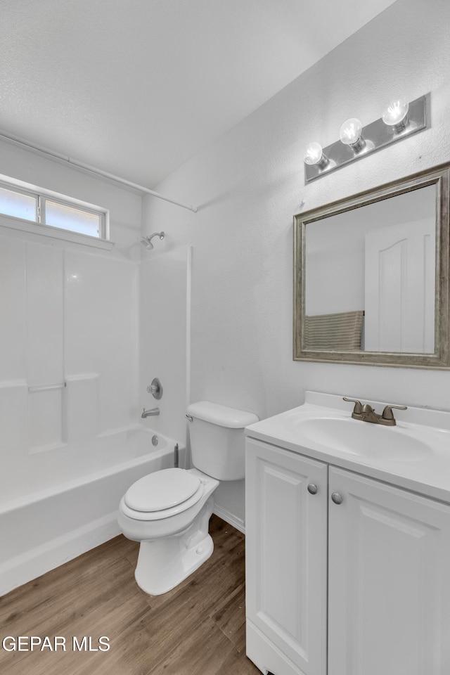 full bathroom featuring washtub / shower combination, wood-type flooring, toilet, and vanity