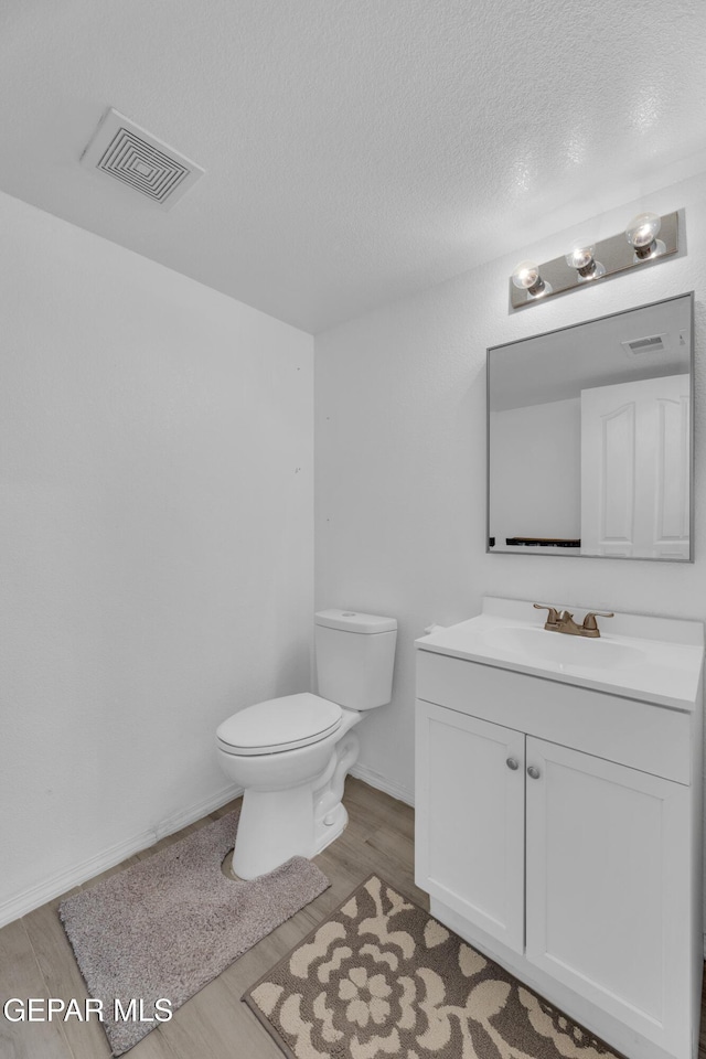 bathroom with vanity, hardwood / wood-style floors, a textured ceiling, and toilet