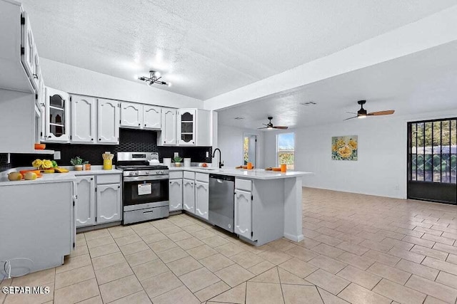 kitchen with sink, appliances with stainless steel finishes, a textured ceiling, white cabinets, and kitchen peninsula