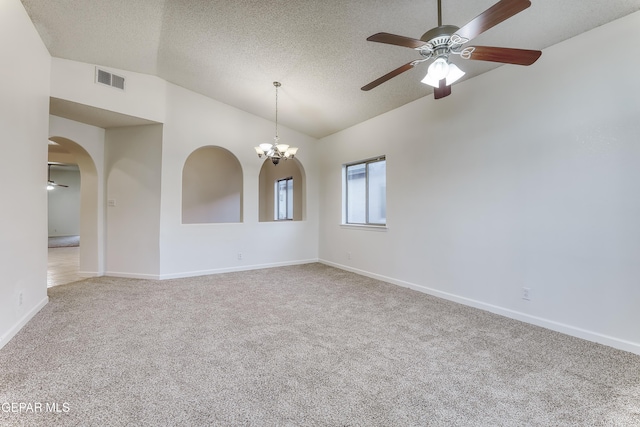 empty room with carpet floors, arched walkways, lofted ceiling, visible vents, and a textured ceiling