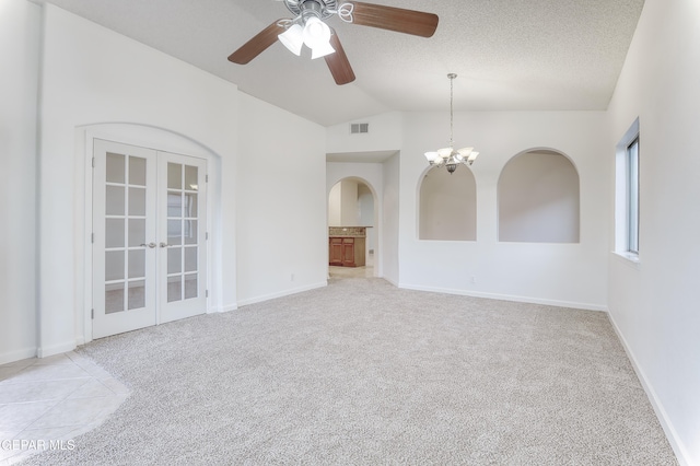 empty room featuring visible vents, light colored carpet, lofted ceiling, a textured ceiling, and french doors