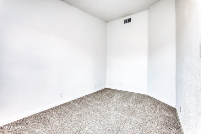 spare room with carpet, visible vents, and baseboards