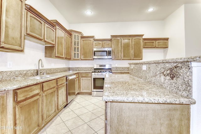 kitchen with light stone counters, glass insert cabinets, stainless steel appliances, a sink, and light tile patterned flooring