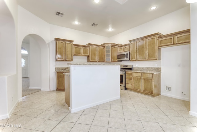 kitchen with brown cabinets, glass insert cabinets, and stainless steel appliances