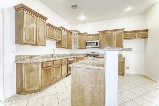 kitchen featuring stainless steel appliances, a sink, visible vents, light stone countertops, and glass insert cabinets