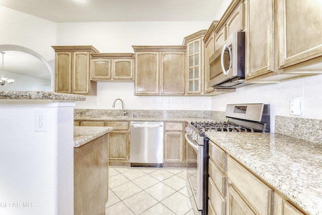 kitchen featuring light tile patterned flooring, stainless steel appliances, a sink, backsplash, and glass insert cabinets