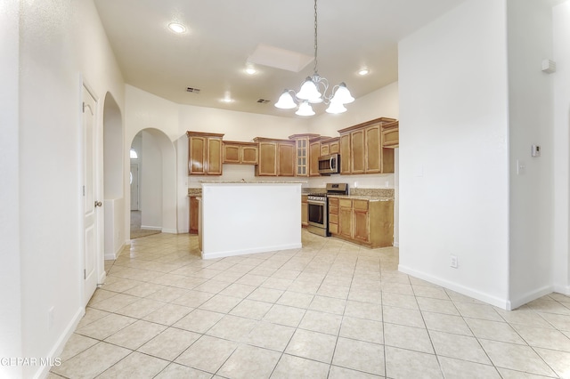 kitchen featuring arched walkways, brown cabinets, stainless steel appliances, glass insert cabinets, and a kitchen island