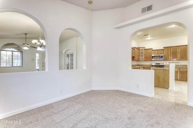 interior space with light colored carpet, visible vents, light tile patterned flooring, ceiling fan, and baseboards