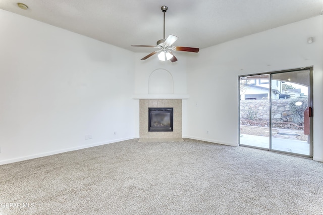 unfurnished living room with carpet, baseboards, ceiling fan, and a tiled fireplace