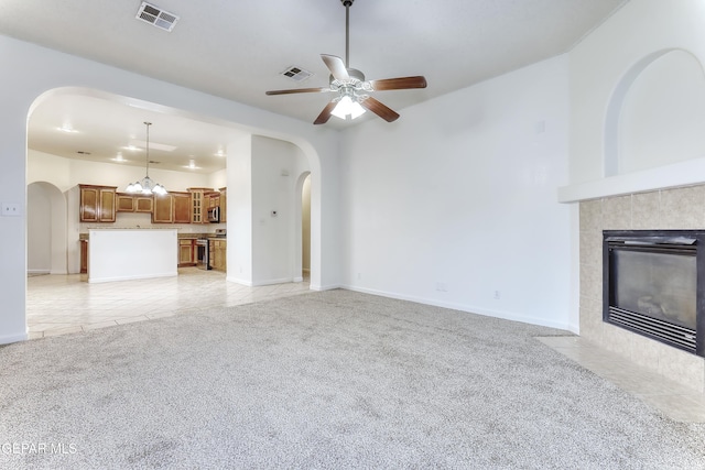 unfurnished living room with light carpet, a fireplace, arched walkways, and visible vents