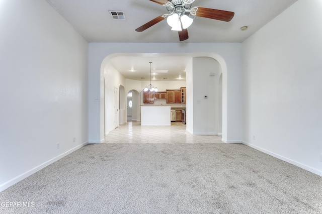 unfurnished living room with visible vents, arched walkways, a ceiling fan, and light colored carpet