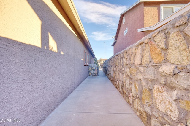 view of side of home featuring fence, a gate, and stucco siding