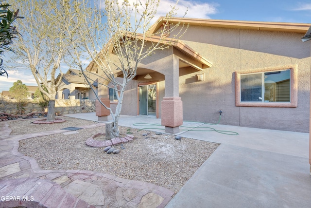 view of front of house with a patio area, fence, and stucco siding