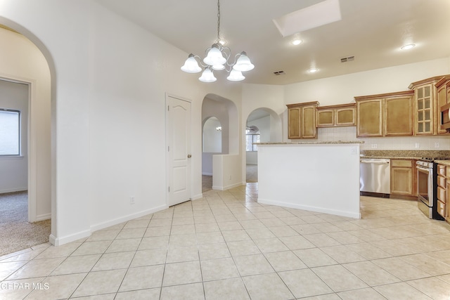 kitchen featuring light tile patterned floors, arched walkways, visible vents, appliances with stainless steel finishes, and glass insert cabinets