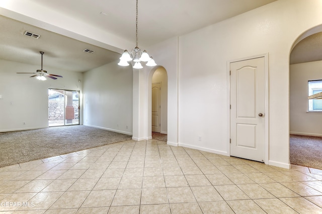 empty room featuring plenty of natural light, visible vents, arched walkways, and light colored carpet