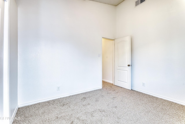 spare room with baseboards, visible vents, and light colored carpet