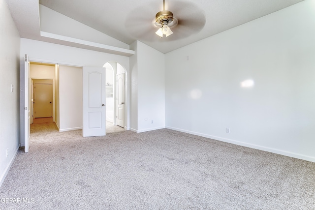 unfurnished bedroom with arched walkways, light colored carpet, a ceiling fan, baseboards, and vaulted ceiling