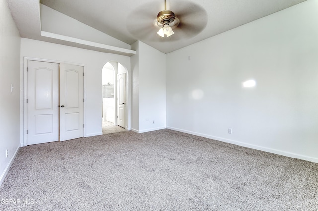 unfurnished bedroom with arched walkways, light colored carpet, a ceiling fan, vaulted ceiling, and baseboards