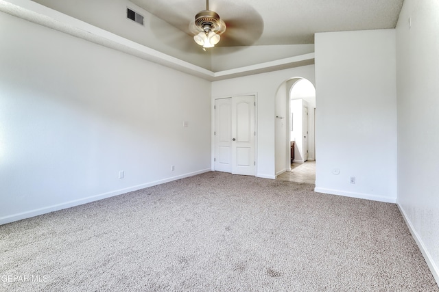 unfurnished bedroom featuring arched walkways, light colored carpet, a ceiling fan, baseboards, and visible vents