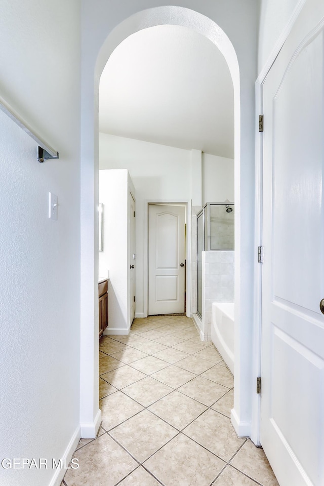 full bathroom featuring a garden tub, vanity, baseboards, tile patterned floors, and a stall shower