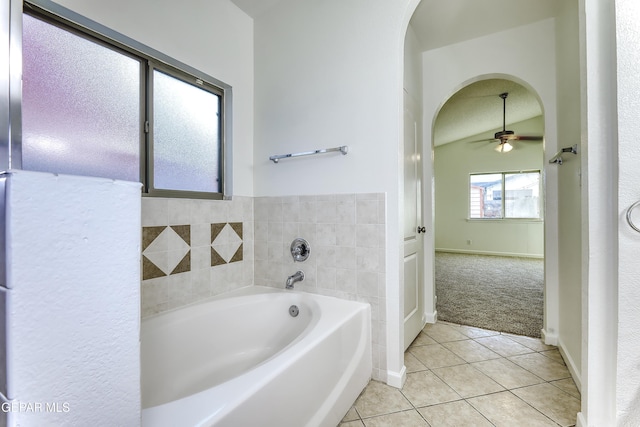 bathroom with a garden tub, a ceiling fan, baseboards, vaulted ceiling, and tile patterned floors