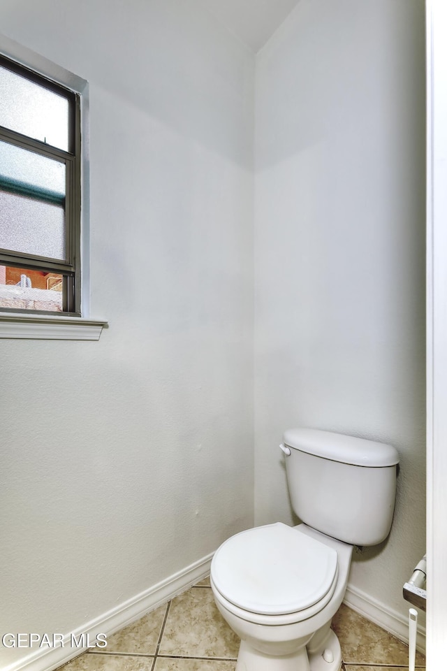 bathroom featuring toilet, baseboards, and tile patterned floors