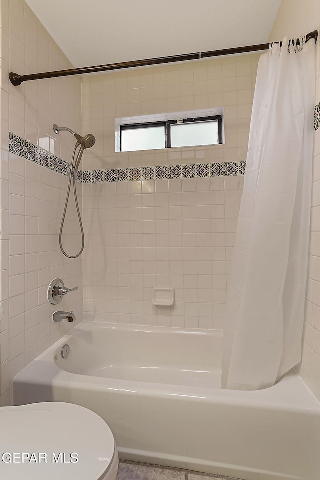 bathroom with shower / tub combo with curtain and toilet