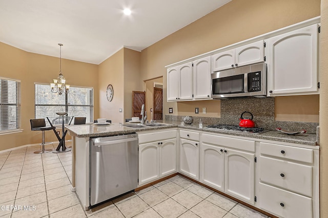 kitchen with pendant lighting, white cabinetry, sink, light tile patterned floors, and stainless steel appliances