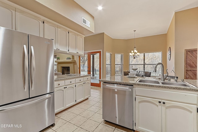 kitchen with light tile patterned flooring, appliances with stainless steel finishes, decorative light fixtures, white cabinetry, and sink