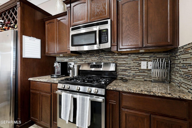 kitchen with tasteful backsplash, dark brown cabinetry, appliances with stainless steel finishes, and light stone countertops