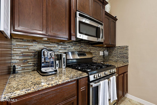 kitchen with light stone counters, stainless steel appliances, and decorative backsplash