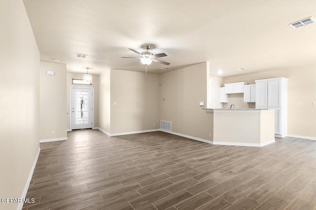 unfurnished living room featuring dark wood-type flooring and ceiling fan