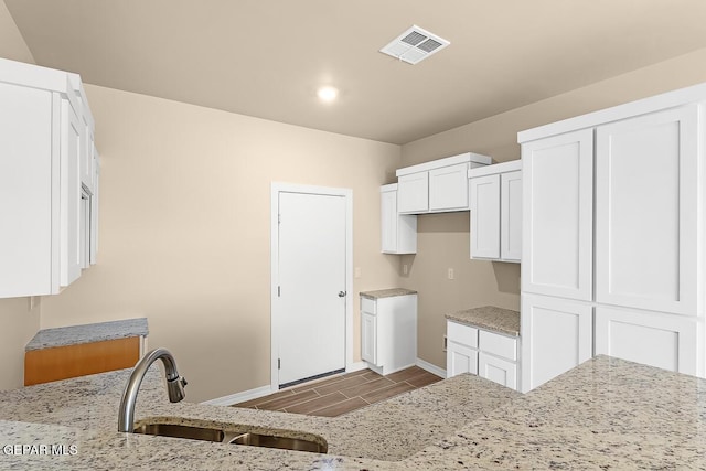 kitchen with light stone counters, sink, and white cabinets