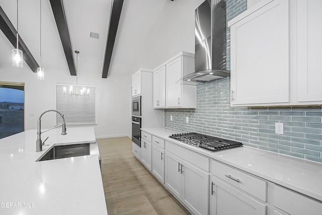 kitchen with decorative light fixtures, sink, white cabinets, stainless steel appliances, and wall chimney exhaust hood