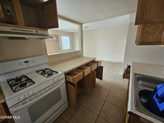 kitchen with a textured ceiling, sink, gas range gas stove, and light tile patterned floors