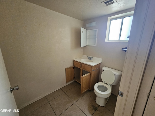 bathroom with tile patterned flooring, vanity, a textured ceiling, and toilet