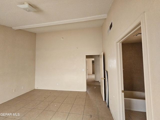 tiled empty room featuring vaulted ceiling