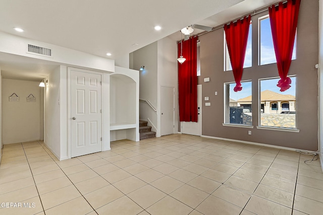 tiled empty room featuring a high ceiling