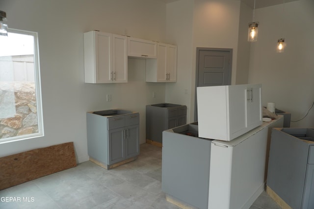 kitchen featuring refrigerator, hanging light fixtures, and white cabinets