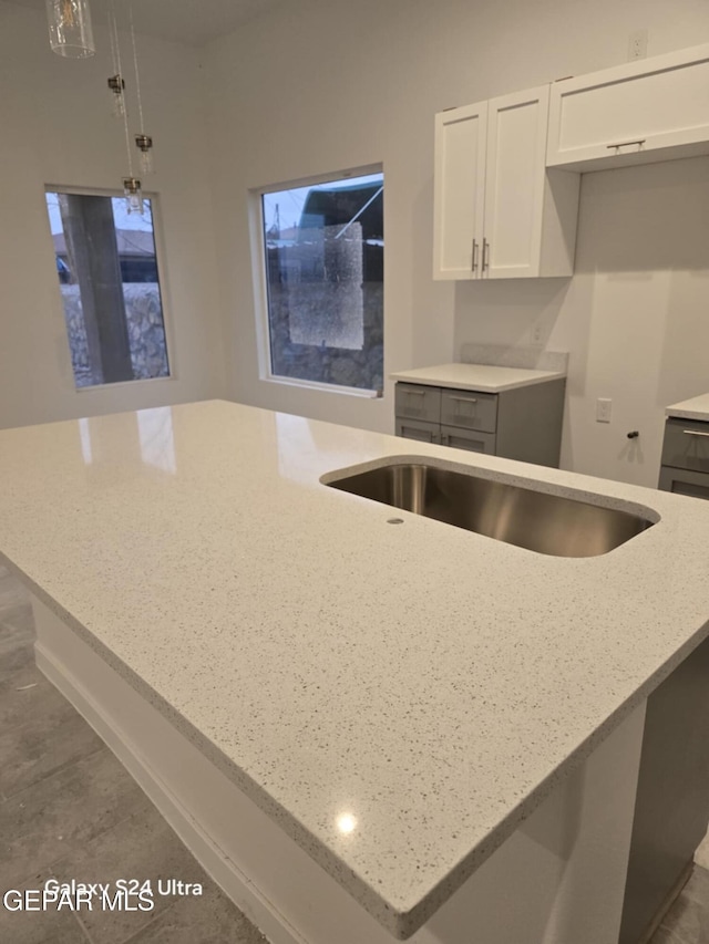 kitchen featuring light stone counters, decorative light fixtures, and white cabinets