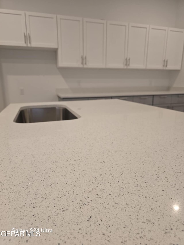 kitchen with white cabinetry and light stone counters