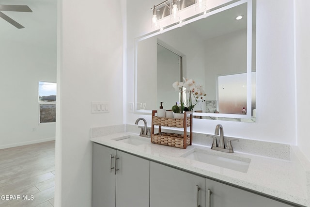 bathroom with double vanity, a ceiling fan, baseboards, and a sink