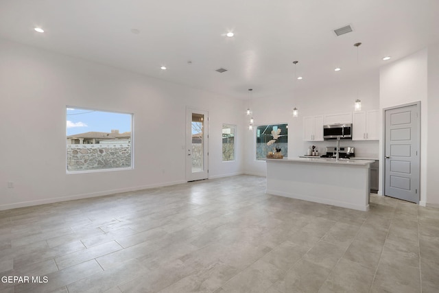 unfurnished living room featuring baseboards, a high ceiling, visible vents, and recessed lighting