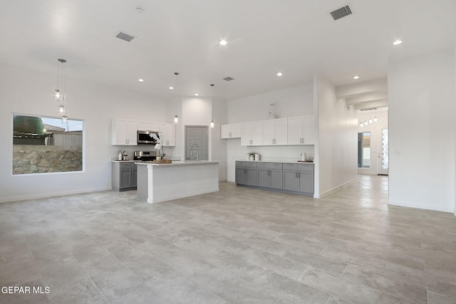 kitchen with open floor plan, stainless steel appliances, gray cabinets, and visible vents