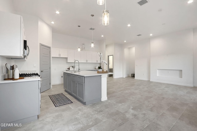 kitchen featuring a kitchen island with sink, a sink, visible vents, white cabinetry, and gray cabinets